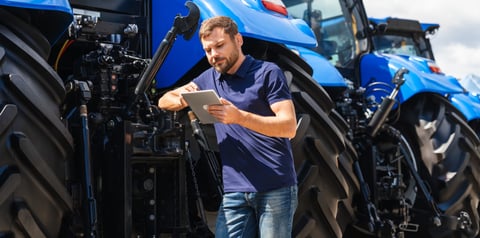 Agricultural engineer working on tablet next to tractor