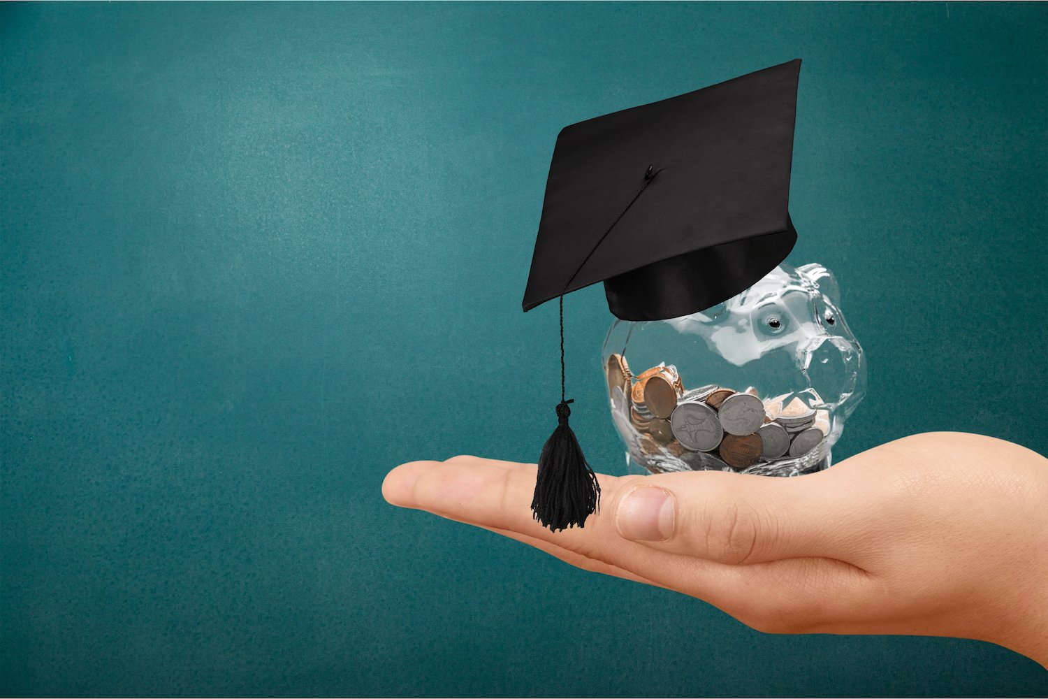 Hand holding jar of change with graduation cap